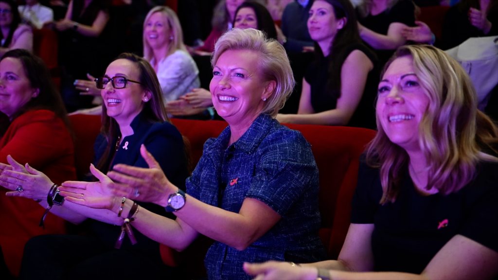 Women in estate agency smiling and clapping at an industry event celebrating professional achievement and community